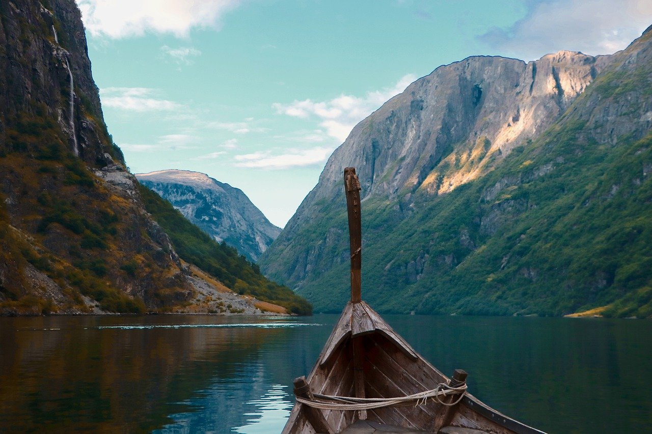 Um barco, navegando em um leito calmo, rodeado de montanhas
